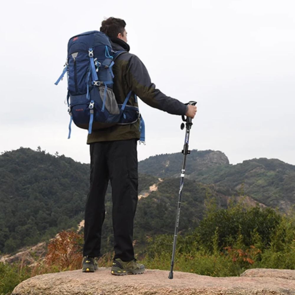 Homme avec baton de marche pliable et ajustable, parfait pour les longues randonnées en montagne.