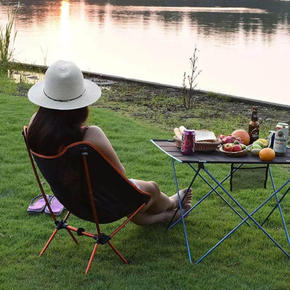 Femme assise sur chaise de camping pliante en tissu imperméable, parfaite pour toutes les conditions météorologiques.